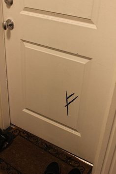 a door with the letter f painted on it and someone's shoes next to it