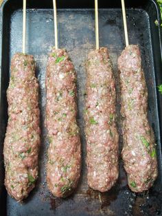 three skewers of meat are on a grill