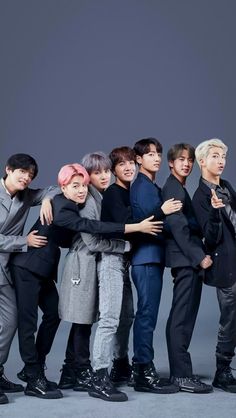 the group of young men are posing together for a photo in front of a gray background