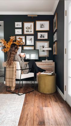 a woman sitting at a desk in front of pictures on the wall