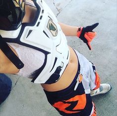 a woman in an orange and white uniform is holding a baseball glove on her hip