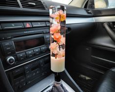 a car dashboard with a vase filled with flowers on it's dash board and radio in the background