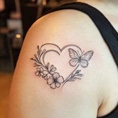 a woman's shoulder with flowers and butterflies in the shape of a heart on it