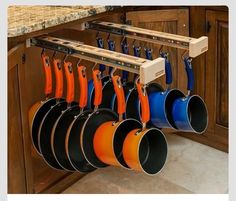 pots and pans are hanging from hooks on the kitchen cabinets in front of an oven