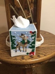 a cross stitch tissue box on top of a wooden table