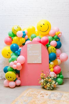 a bunch of balloons that are in the shape of smiley faces on a pink door