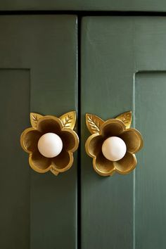 an egg is sitting in the center of a golden flower on a green door handle