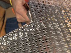 a person cutting something with a knife on a metal table top that has holes in it