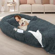 a woman laying on top of a dog bed with a white dog in it's lap