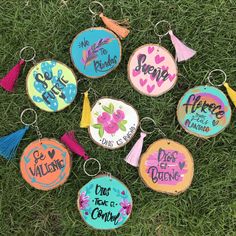 painted wooden key chains with tassels on them in the shape of flowers and words