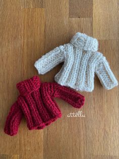 two knitted sweaters sitting on top of a wooden floor