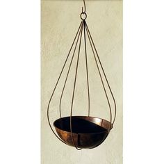 a metal hanging bowl on a wall with an iron wire loop around the bottom and sides