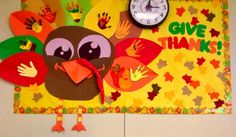 a bulletin board with an owl and handprints on it, along with a clock