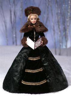 a barbie doll wearing a black dress and fur hat in the snow with trees behind her