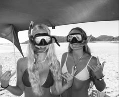 two women wearing goggles and bikinis on the beach