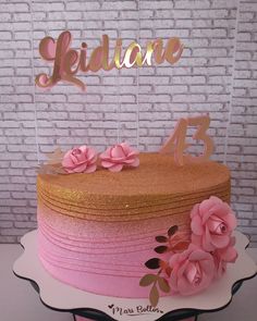 there is a cake with pink flowers on the top and gold lettering that says, i do not know what it is