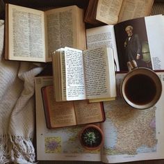 an open book and cup of coffee on top of a map with other books around it