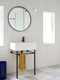 a white sink sitting under a round mirror