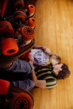 two children laying on the floor with skateboards in the background and one child holding his head