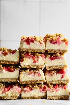 a stack of strawberry cheesecake bars sitting on top of a counter next to a glass of milk