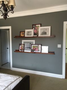 a room with pictures on the wall and shelves above it, along with other items