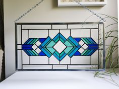 a stained glass window hanging from a chain next to a potted plant and clock