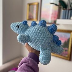 a hand holding a crocheted stuffed toy in the shape of a seahorse