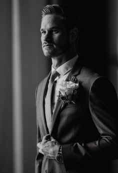 a man in a suit and tie is posing for a black and white photo with his hands on his hips