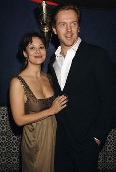 a man and woman standing next to each other in front of a wall with an award on it