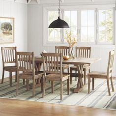 a dining room table and chairs with a rug on the floor in front of it