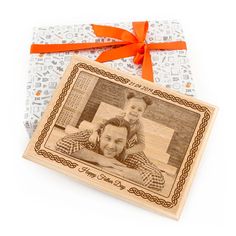 a wooden photo frame with an orange ribbon around it and a gift wrapped in white paper