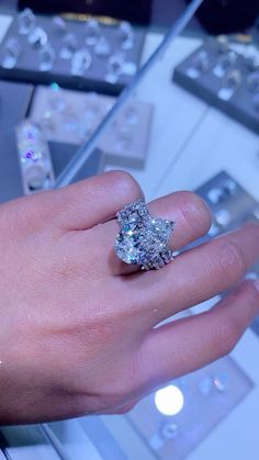 a woman's hand with a diamond ring on it, surrounded by other jewelry items