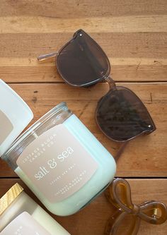 two candles with sunglasses on top of them sitting next to each other and one candle has a label that says salt & sea