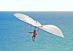 a man flying through the air while riding a glider over blue water in an ocean