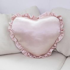 a pink heart shaped pillow sitting on top of a white couch