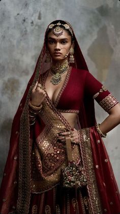 a woman in a red and gold outfit with her hands on her hips, posing for the camera