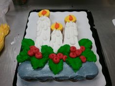 a decorated cake with candles and holly leaves on the top, sitting on a table