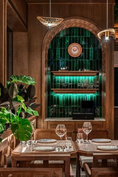 a restaurant with wooden tables and chairs, green tiles on the wall behind them is an arched window