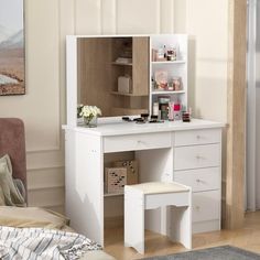 a white dressing table with a mirror and stool in a living room next to a bed