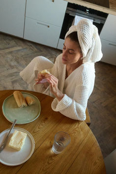 a woman sitting at a table with food in front of her and eating bread on the plate