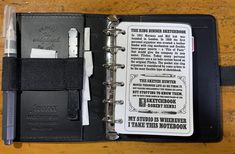 an open notebook with writing on it and a pen in the pocket next to it