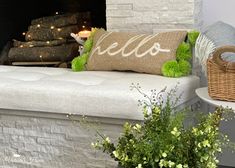 a white couch sitting next to a fire place filled with plants and pillows on top of it