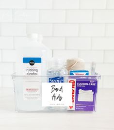 cleaning supplies are sitting in a clear container on a countertop next to a white brick wall