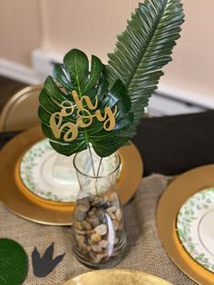 there is a vase with some plants in it and plates on the table next to it