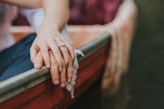 a person sitting in a boat with their hands on the edge