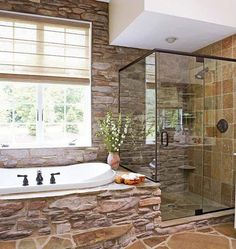 a bathroom with stone walls and a large tub next to a walk - in shower