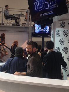 people are standing around in front of a big screen tv at an indoor convention center