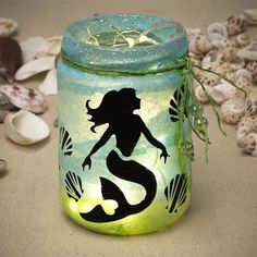 a glass jar with a mermaid painted on it