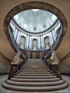 an ornate staircase with statues on either side and a domed ceiling above it in a building