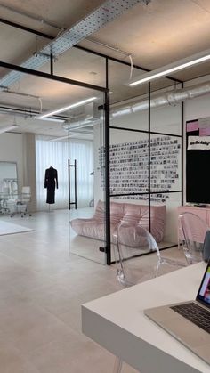 a laptop computer sitting on top of a white table next to a glass display case